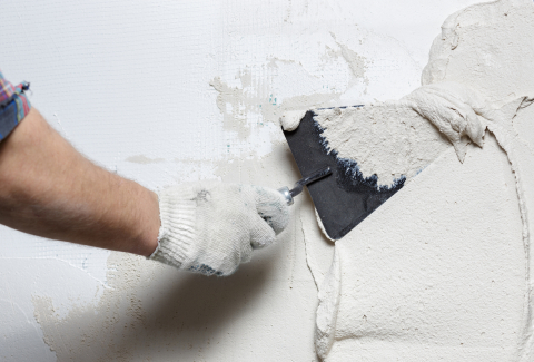 Construction worker with trowel plastering a wall